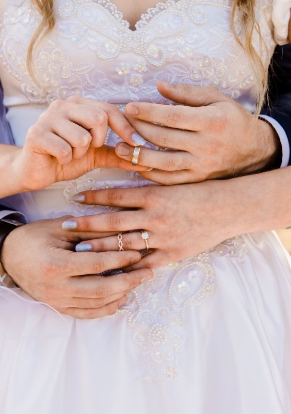 Spouse hands around waist putting on rings